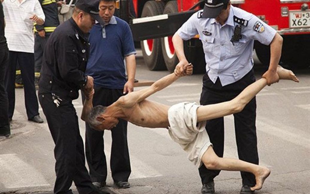 Китай, Пекін. Китайська поліція затримує літню людиню, яка вилізла на рекламний щит і спробувала покінчити із собою, стрибнувши на землю. Рівень самогубств серед літніх людей в Китаї став тривожно високим. / © AFP