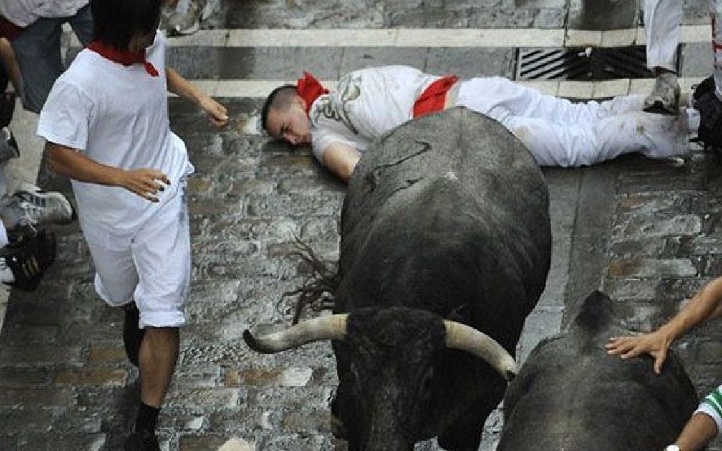 Іспанія, Памплона. Чоловік лежить на землі після того, як по ньому пробіг бик. Традиційні забіги з биками по вулицям міста проводять у Памплоні протягом 9 днів фестивалю Сан-Фермін . / © AFP