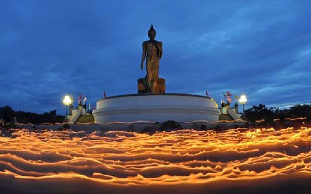 Таїланд, Бангкок. Стежки від свічок, які тримають буддисти під час урочистої ходи навколо статуї Будди. Буддисти віддали данину поваги Будді під час святкування Дня Асаха Буча у передмісті Бангкока. / © AFP