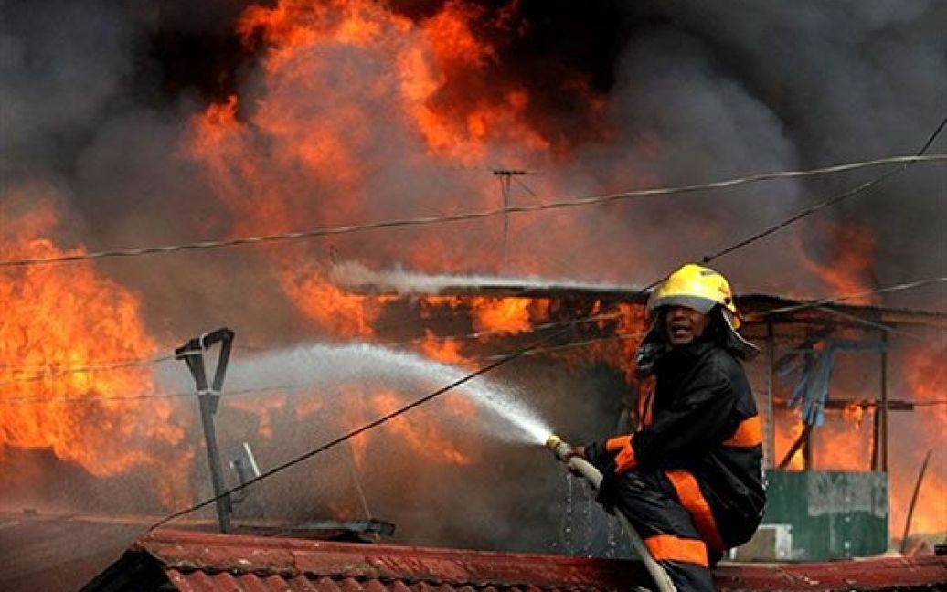 Філіппіни, Маніла. Пожежний намагається загасити вогонь під час сильної пожежі у нетрях фінансового району Маніли. Вогонь залишив без даху над головою понад 2000 сімей. / © AFP