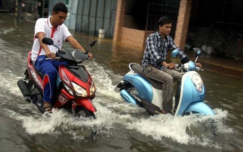 Таїланд, Наратхіват. Тайські чоловіки на мотоциклах їдуть вулицею, затопленою в результаті сильних дощів. Через повені на півдні Таїланду загинули троє людей і постраждало ще десятки тисяч. / © 