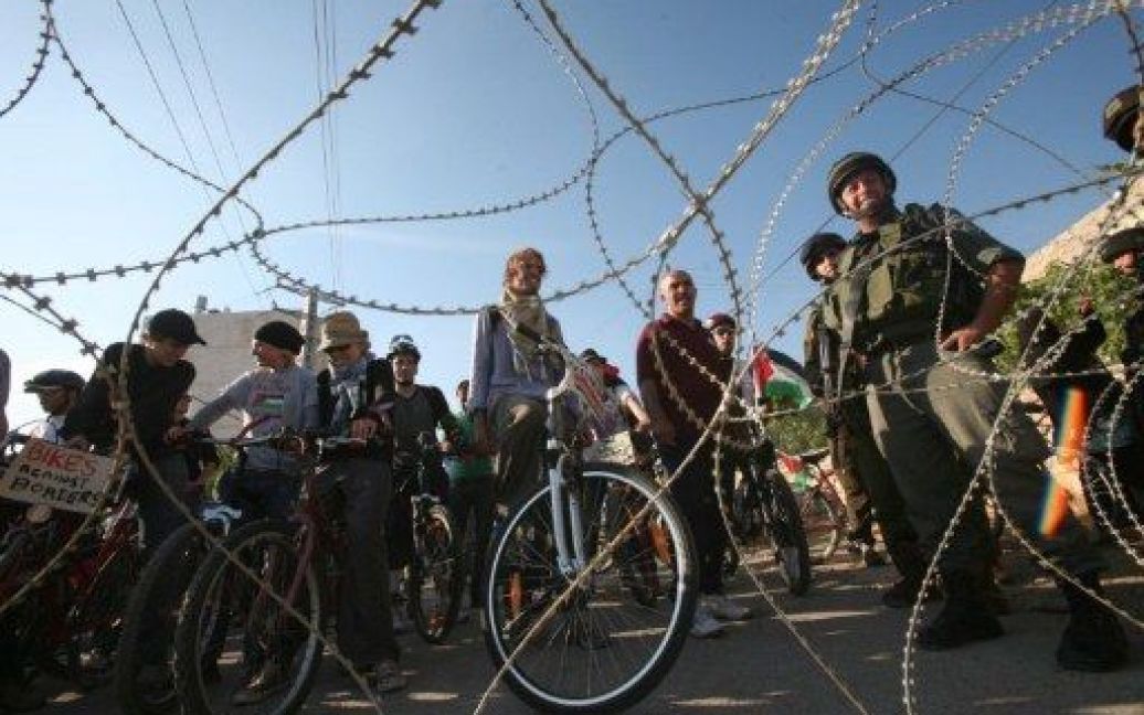 Хеврон. Палестинські та зарубіжні велосипедисти чекають за колючим дротом та кордоном ізраїльських сил безпеки, щоб провести велопробіг під гаслом "Велосипеди без кордонів" через палестинську дорогу, закриту ізраїльськими військами. / © AFP
