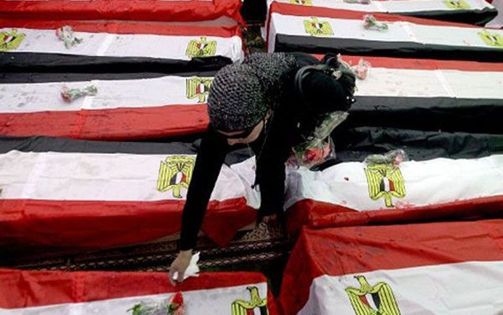 Єгипет, Каїр. Єгипетська жінка покладає квіти на драпіровані національними прапорами труни 19 непізнаних жертв, які були вбиті під час революції у Єгипті. / © AFP