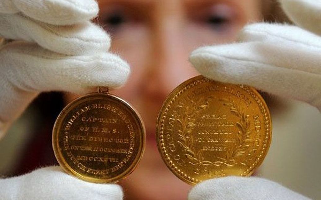 Австралія, Мельбурн. Співробітник "Nobles Numismatics" тримає дві цінні золоті медалі, якими був нагороджений капітан Вільям Блай. Медалі продадуть в Мельбурні, де відбудеться один з найбільших "морських історичних" аукціонів. / © AFP