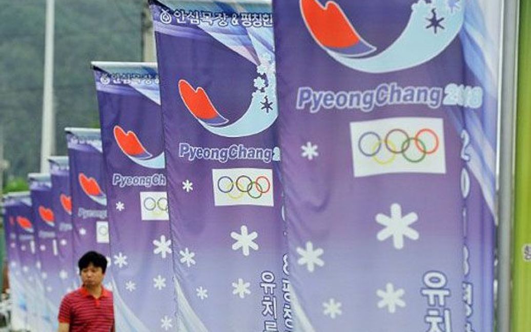Республіка Корея, Пхенчхан. Чоловік проходить повз банери логотипом південнокорейського гірського курорту Пхенчхана, який був обраний для проведення Зимових Олімпійських ігор у 2018 році. / © AFP