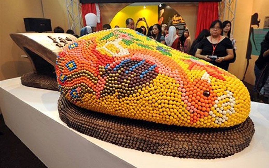 Малайзія, Куала-Лумпур. Відвідувачі роздивляються взуття "Баба Ньоня", виготовлене з шоколаду, на міжнародній виставці взуття у Малайзії. "Баба Ньоня" зроблене з 130 кг шоколаду, занесене до Книги рекордів Малайзії, як найбільший шоколадний черевик. / © AFP