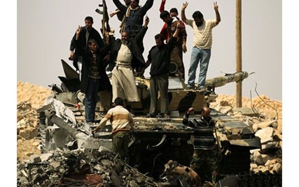 Лівійська Арабська Джамахірія, Аждабія. Лівійські повстанці святкують на спаленому танку військ Муаммара Каддафі після повернення собі стратегічного міста Аждабія. / © AFP