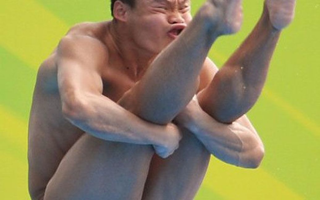 Китай, Шанхай. Китайський спортсмен Мін Він виконує стрибок з 1-метрового трампліна під час фінальних змагань на чемпіонаті світу з плавання FINA у відкритому басейні в Шанхаї. / © AFP