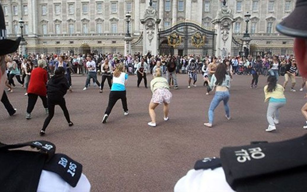 Великобританія, Лондон. Поліцейські дивляться на студентів Університету Східного Лондона, які беруть участь у "королівському флешмобі" Big Dance перед Букінгемським палацом у Лондоні. / © AFP