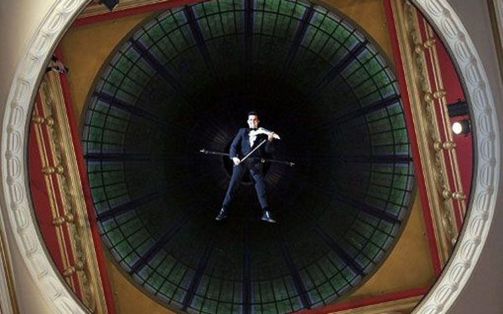 Австралія, Сідней. Австралійський музикант Шензо Грегоріо грає на електричній скрипці, доки він висить під куполом історичної будівлі Королеви Вікторії в Сіднеї. Шензо зіграв кілька складних класичних композицій, висячи на висоті 25 метрів у повітрі. Фото AFP/Камерон Міллз / © AFP