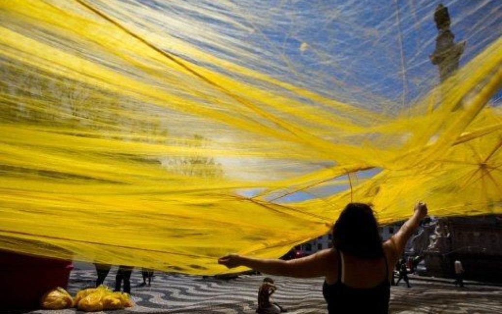 Португалія, Лісабон. Жовті волокна розміщують в інсталяції італійського художника Донато Сарторі "Міське маскування", яка вкрила всю площу Росіо у Лісабоні. / © AFP