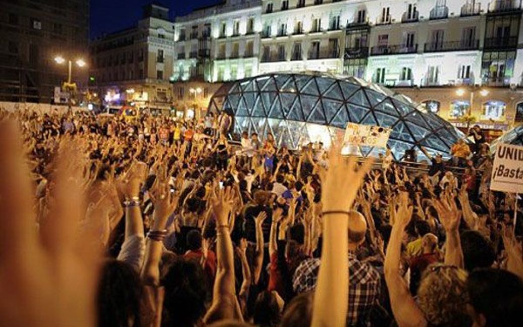 Іспанія, Мадрид. Демонстранти піднімають руки під час останніх зборів у наметовому містечку на площі Пуерта дель Соль в Мадриді. Протестуючі, які провели на акціях протесту цілий місяць, планують демонтувати свій старий табір, який став символом руху проти істеблішменту. / © AFP