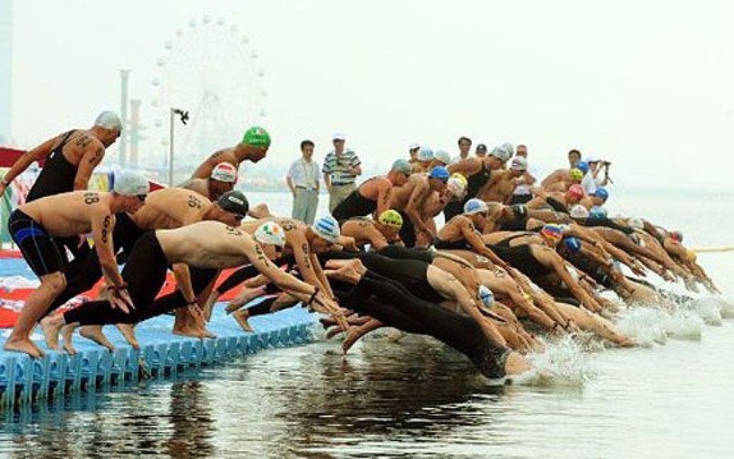Китай, Шанхай. Спортсмени починають змагання із плавання на 10 кілометрів серед чоловіків на пляжі в Шанхаї в рамках чемпіонату світу з плавання FINA. / © AFP