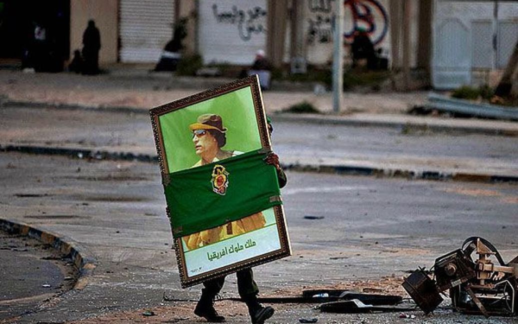 Лівія, Місрат. Лівійський урядовий солдат несе портрет Муаммара Каддафі вулицею міста Місрат, на схід від Тріполі. / © 