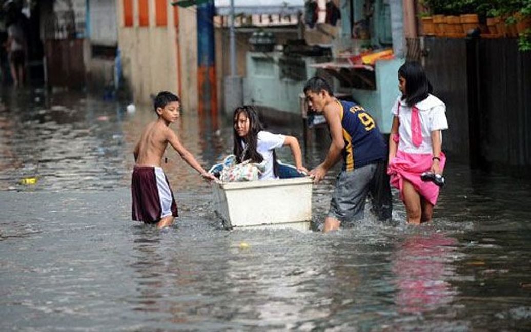 Філіппіни, Маніла. Мешканці пробираються затопленою вулицею після сильного дощу, викликаного тайфуном Нок-тен. В результаті тропічного шторму, одна людина загинула, тисячі були змушені покинути свої затоплені будинки. / © AFP