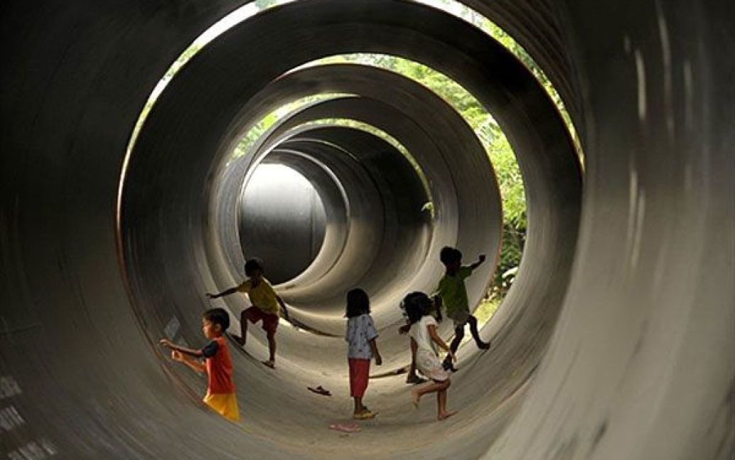 Філіппіни, Маніла. Діти грають всередині сталевої труби, яку будуть використовувати для прокладання водопроводу і каналізації під час будівництва системи водопостачання у Манілі. / © AFP