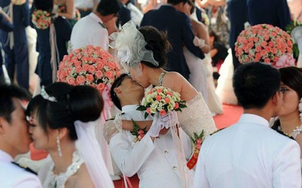 Тайвань, Тайбей. Пара цілується під час масової церемонії весілля для військових в Тайбеї. Загалом 268 нових пар візьмуть участь у масовому весіллі на честь святкування 100-річчя заснування Тайваня. / © AFP
