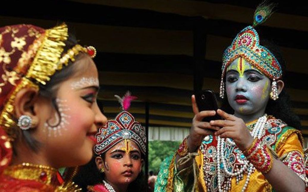 Індія, Калькутта. Хлопчик в костюмі бога Крішни фотографує дівчинку в костюмі богині Радхі перед участю у святі "Ратха-ятра", яке провело Міжнародне товариство свідомості Крішни в Калькутті. / © AFP