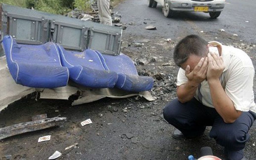 Китай, Сяньтао. Чоловік сумує на місці транспортної пригоди, де зіткнулись вантажівка та міжміський автобус, який перекинувся і загорівся. Щонайменше 26 людей загинули, більше 30 осіб отримали поранення в результаті аварії. / © AFP