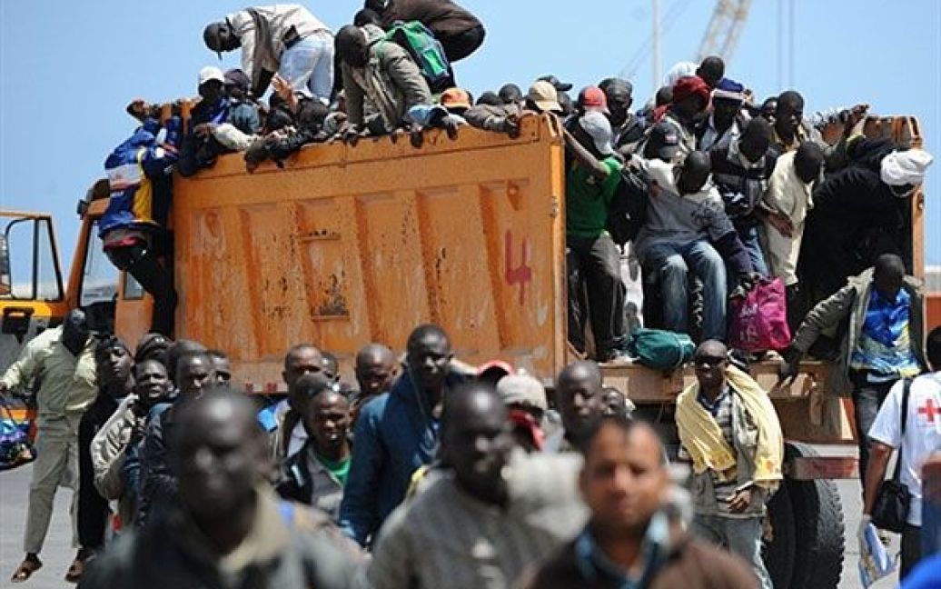 Лівійська Арабська Джамахірія, Місрата. Мігранти, які рятуються з Лівії, прибувають в кузові вантажівки до порту міста Місрата для посадки на борт судна Міжнародної організації міграції. / © AFP