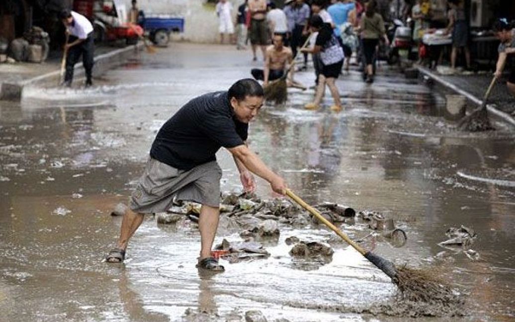 Китай, Ланкі. Місцеві мешканці прибирають бруд, який залишився на вулицях після того, як спали паводкові води у східній китайській провінції Чжецзян. В Китаї від сильних повенів загинули більше 260 осіб. / © AFP