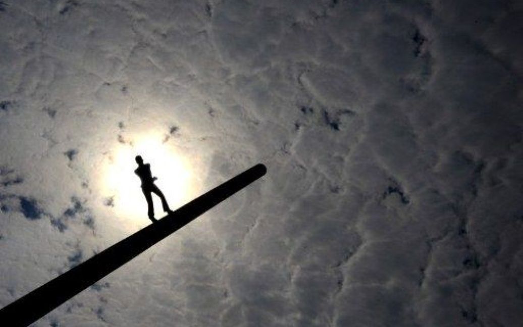 Німеччина, Кассель. Сонце виходить з-за хмар на тлі скульптури "Людина, яка йде до неба" американського художника Джонатана Боровські в місті Кассель. / © AFP