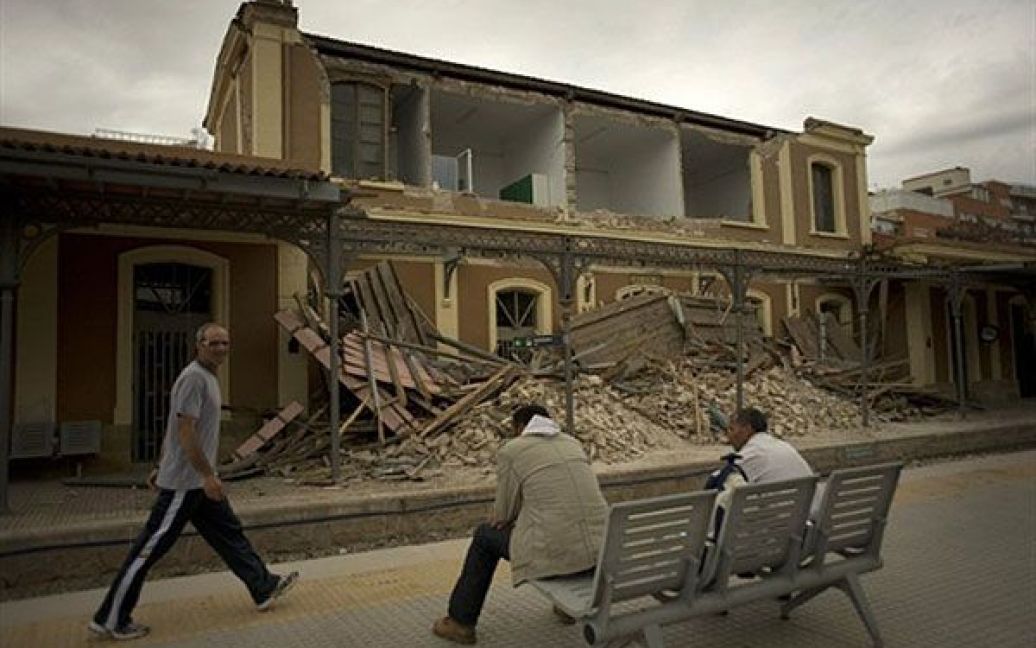 Іспанія, Лорка. Чоловіки сидять на лавці перед знищеною землетрусом залізничною станцією у місті Лорка. В Іспані сталося два підземні поштовхи магнітудою до 5,1 балів, в результаті яких загинули щонайменше 9 осіб, були зруйновані тисячі будинків. / © AFP