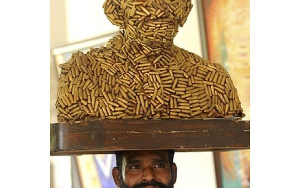 Індія, Амрітсар. Індійський працівник несе на голові скульптуру, яка зображає лідера Махатму Ганді, виготовлену з символічних "куль", під час відкриття Виставки індійського мистецтва 2011 у Індійській академії образотворчого мистецтва в Амрітсарі. / © AFP