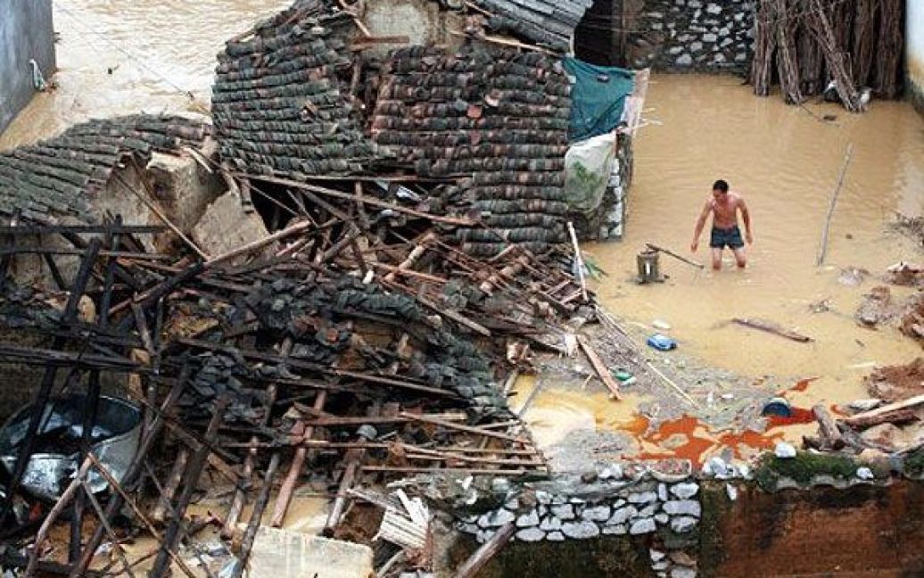 Китай, Лайбін. Людина намагається врятувати речі зі свого будинку, пошкодженого під час повені у провінції Гуансі. Китай потерпає від сильних дощів, більше 55 тисяч осіб були евакуйовані, більше 100 осіб загинули. / © AFP