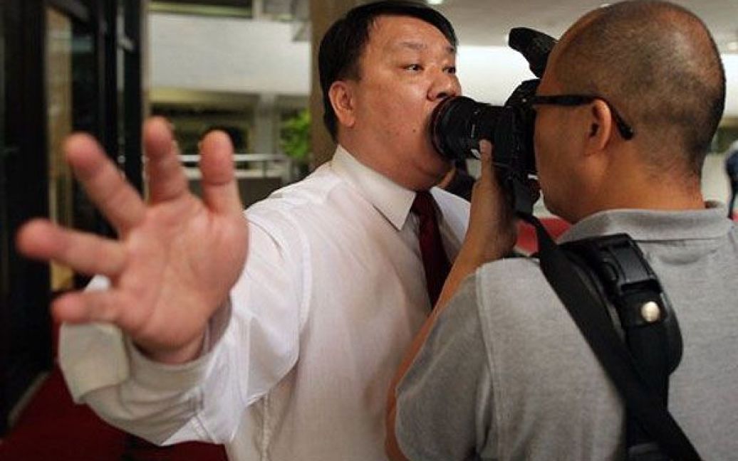 Китай, Гонконг. Охоронець намагається зупинити фотографа, який знімає учасників акції протесту, що закликають звільнити затриманого тайського правозахисника Сомйота Пруксакасемсука, перед тайським консульством в Гонконзі. / © AFP