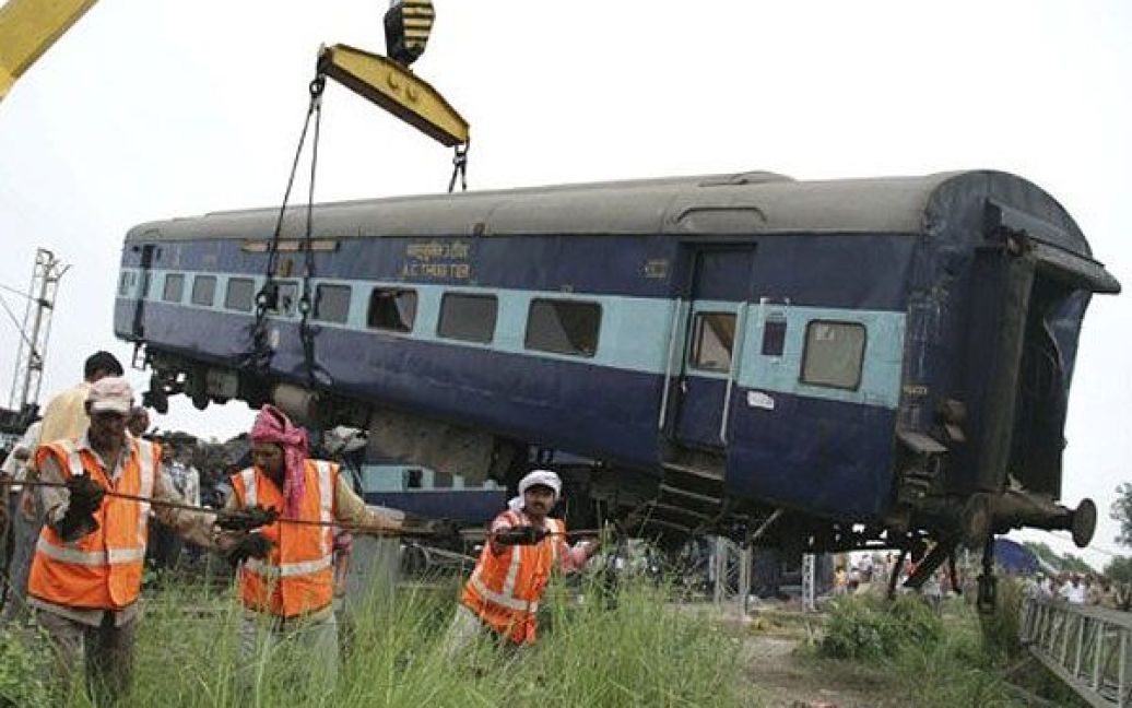Індія, Фатехпур. Індійські рятувальники краном піднімають вагон на місці залізничної аварії в Фатехпурі. Два пасажирські поїзди зійшли з рейок, в результаті чого 63 людини загинули, більше 200 отримали поранення. / © AFP
