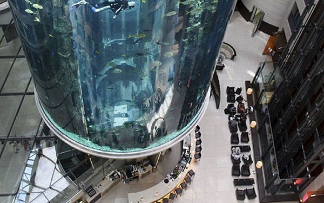 Німеччина, Берлін. Аквалангісти чистять величезний акваріум "AquaDom", який встановили у лобі готеля Radisson Blu в центрі Берліна. Акваріум вміщає близько 1 млн літрів води, в ньому мешкають приблизно 1500 тропічних риб. Всередині акваріуму працює ліфт. / © AFP