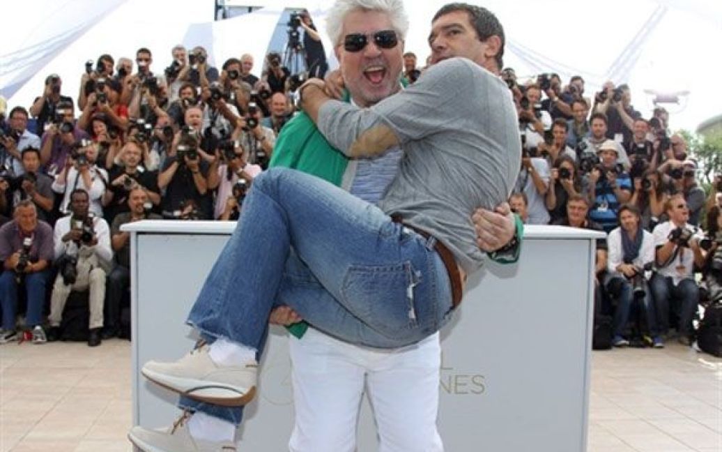 Франція, Канни. Іспанського актора Антоніо Бандераса тримає на руках іспанський режисер Педро Альмодовар під час фотосесії для фільму "Шкіра, в якій я живу" на 64-му Каннському кінофестивалі. / © AFP