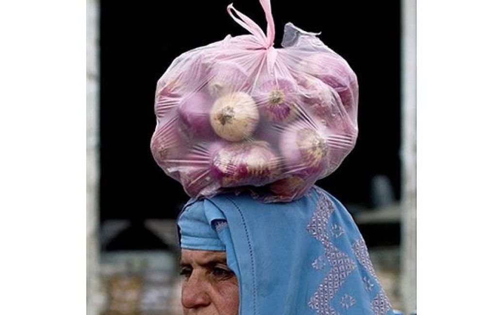 Афганістан, Кабул. Афганська жінка несе на голові пакет цибулі. Експерти вважають, що смерть Усами бен Ладена, можливо, призведе до політичного рішення і початку переговорів між Заходом та рухом "Талібан". / © AFP