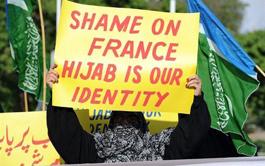 Пакистан, Ісламабад. Активістка Пакистанської фундаменталістської ісламської партії "Джамаат-і-Ісламі" у паранджі тримає плакат під час акції протесту в Ісламабаді. Жінки виступили проти введення заборони на носіння паранджі у Франції. / © AFP