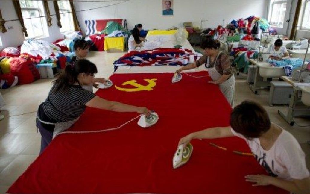 Китай, Пекін. Китайські працівники прасують прапор Комуністичної партії Китаю на заводі в Пекіні. Правляча комуністична партія Китаю, яка нараховує більше 80 мільйонів членів, готується до святкування 90-річчя 1 липня 2011 року. / © AFP
