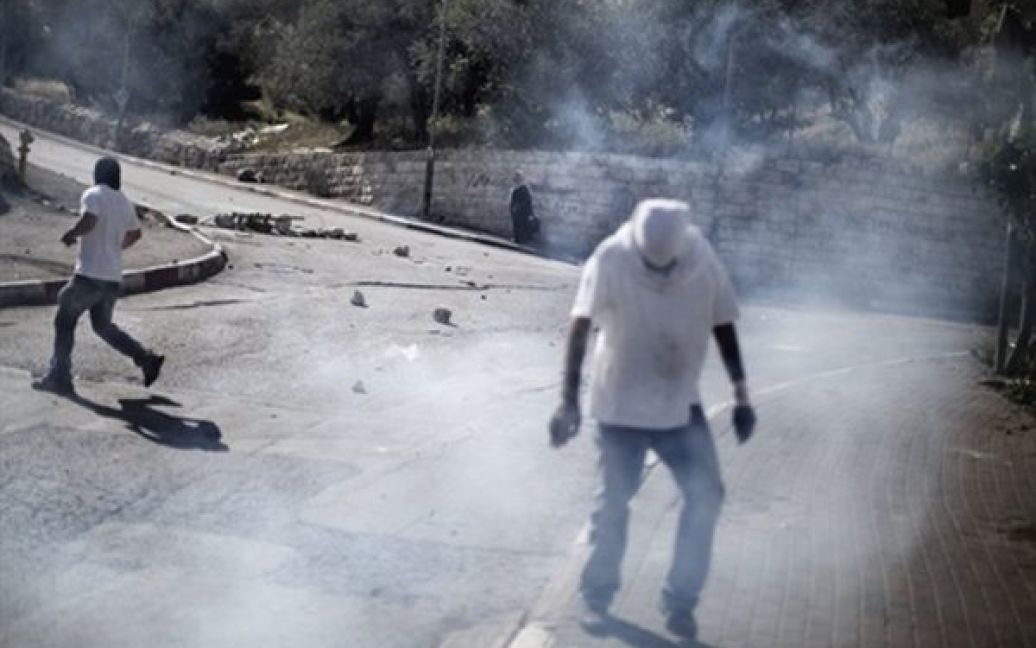 Ізраїль, Єрусалим. Палестинські демонстранти втікають від хмари сльозоточивого газу, який застосували ізраїльські поліцейські, під час заворушень у районі Сильван. / © AFP