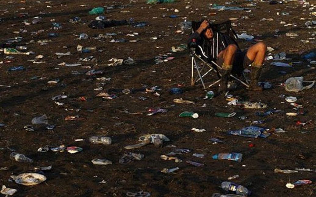 Великобританія, Гластонбері. Відвідувач музичного фестивалю сидить серед сміття після завершення останнього виступу на п&#039;ятиденному фестивалі у Гластонбері. / © AFP