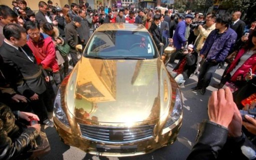 Китай, Нанкін. Натовп роздивляється позолочений розкішний спортивний автомобіль Infiniti, виставлений перед ювелірним магазином у Нанкіні. / © AFP