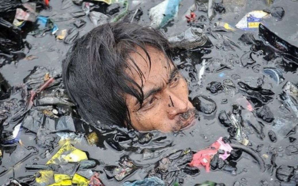 Філіппіни, Маніла. Людина плаває серед сміття і мотлоху у пошуках речей після сильної пожежі у нетрях неофіційних поселенців у передмісті Маніли. Близько тисячі жителів постраждали під час пожежі, але про жертви не повідомлялося. / © AFP