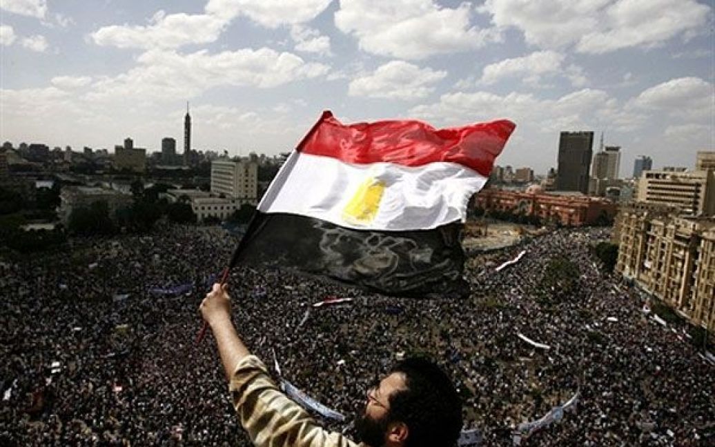 Єгипет, Каїр. Єгиптянин розмахує національним прапором під час багатотисячної демонстрації на площі Тахрір в Каїрі через два місяці після того, як президент Єгипту Хосні Мубарак був усунений від влади. Демонстранти вимагали, щоб від влади були усунені колишні чиновники. / © AFP