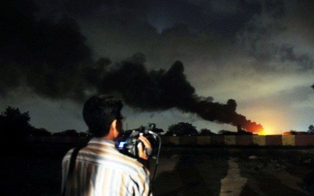 Пакистан, Карачі. Працівник ЗМІ спостерігає, як полум&#039;я і дим піднімаються над пакистанською базою ВМФ після нападу бойовиків в Карачі. Бойовики Талібану, озброєні ракетами і вибухівкою, штурмували базу, знищивши два літаки-розвідники. / © AFP