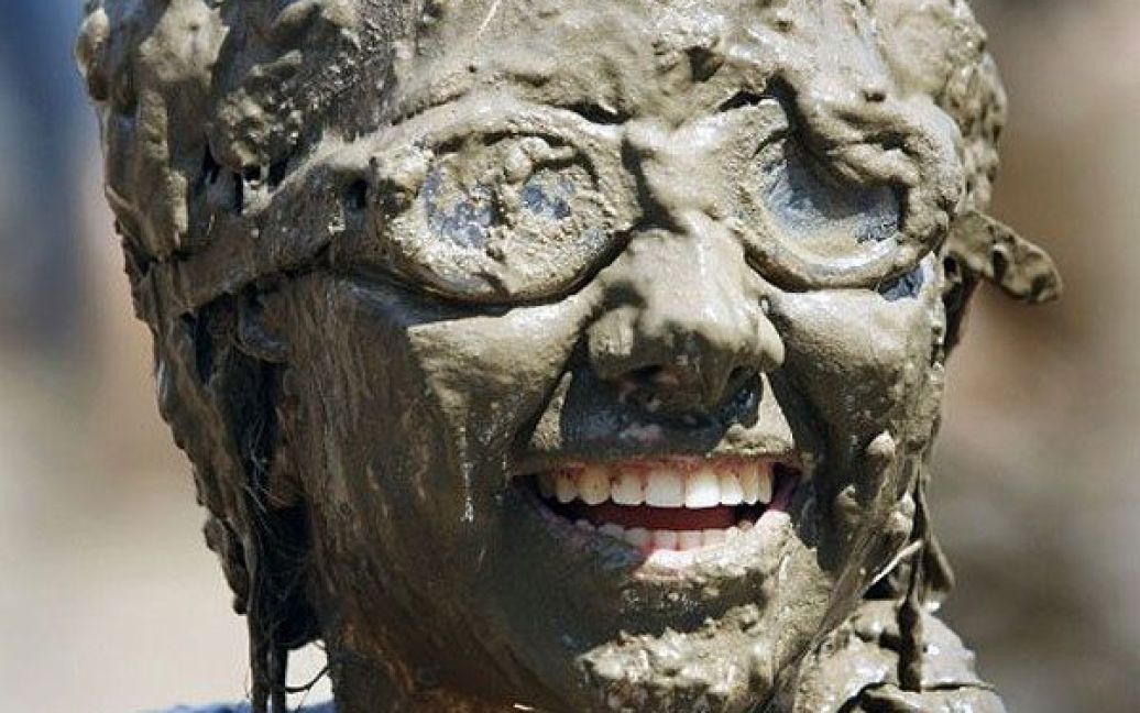 США, Вестленд, штат Мічіган. Дівчинка посміхається під час участі у фестивалі бруду Wayne County&#039;s 2011. Під час щорічного розважального заходу люди обмазуються у багнюці, яку спеціально готують з 75 тисяч літрів води і 200 тонн землі. / © AFP