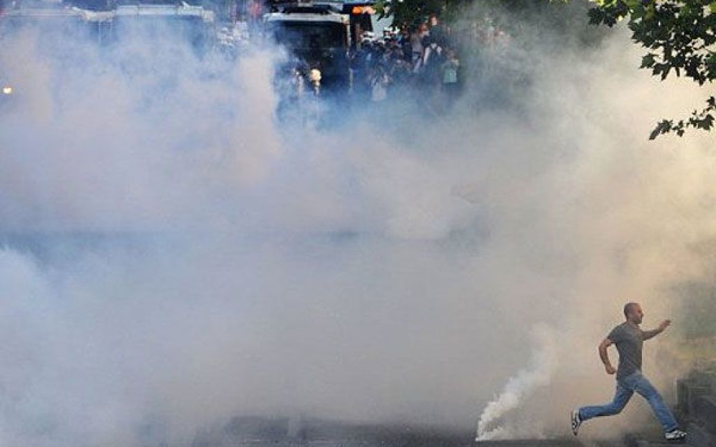 Туреччина, Стамбул. Демонстрант тікає від сльозогінного газу та димових шашок під час зіткнень між курдськими і турецькими лівими групами та співробітниками ОМОНу в Стамбулі. / © AFP