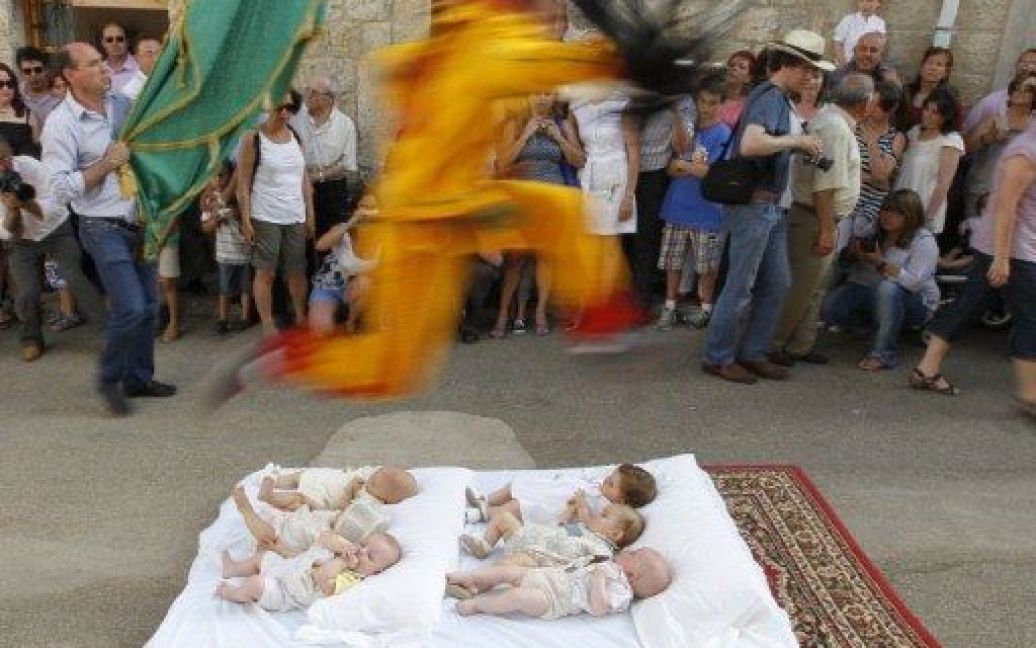 Іспанія, Кастрільо-де-Мурсія. Чоловік у костюмі диявола стрибає через немовлят, які лежать на матраці, під час святкування "Ель Colacho". Стрибки через дітей є традиційним іспанським ритуалом, який виконують, починаючи з 1620 року, на честь католицького свята Тіла Христового. / © AFP