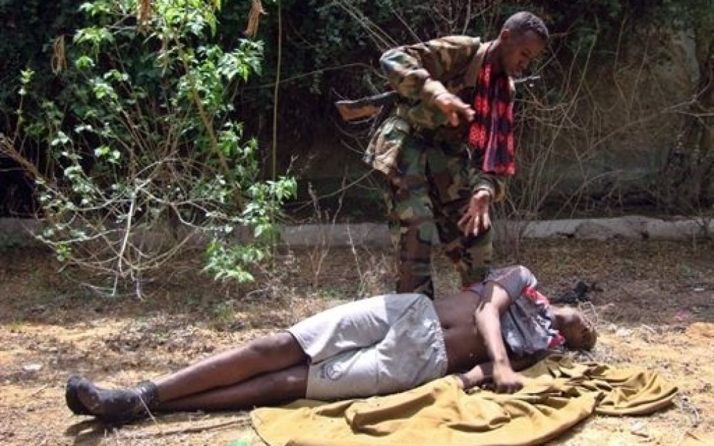 Сомалі, Могадішо. Сомалійський солдат оглядає тіло передбачуваного ісламістського бийця, який був убитий біля КПП у південному Могадішо під час важких боїв між Африканським союзом та бійцями Аль-Шабаба. / © AFP
