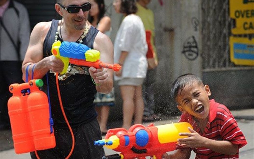 Таїланд, Бангкок. Тайські діти і іноземний турист бризкають водою один на одного під час святкування тайського Нового року в Бангкоку. / © AFP