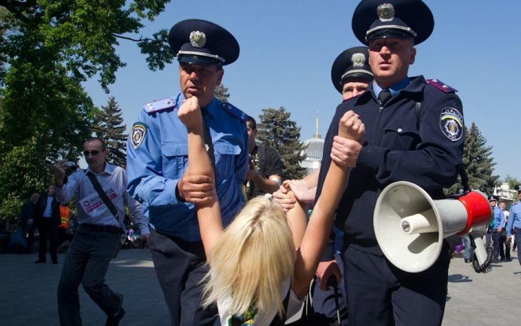 Через кілька секунд після початку топлес-акції протесту працівники міліції взяли дівчат за руки та ноги і віднесли до міліцейських автобусів. / © Жіночий рух FEMEN