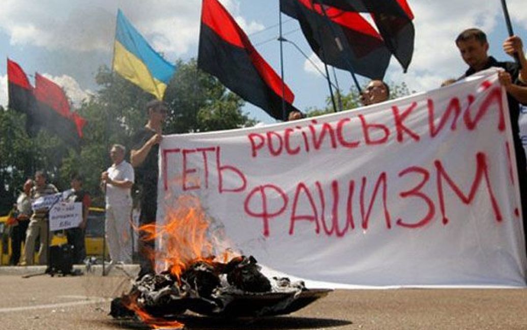 Україна, Київ. Українські націоналісти тримають плакат "Геть російський фашизм" після урочистого спалення ленти Святого Георгія під час мітингу перед будівлею посольства РФ в Києві. В Україні відзначили 70 років з моменту вторгнення фашистської Німеччини на територію СРСР. / © AFP