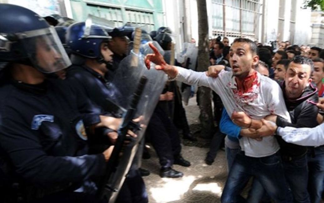 Алжир. Поранений протестувальник намагається поговорити з поліцейськими. У Алжирі спалахнули акції протесту студентів, незадоволених владою. На даний момент будь-які демонстрації на півночі Алжиру заборонені, але молодь все одно виходить на вулиці. / © AFP